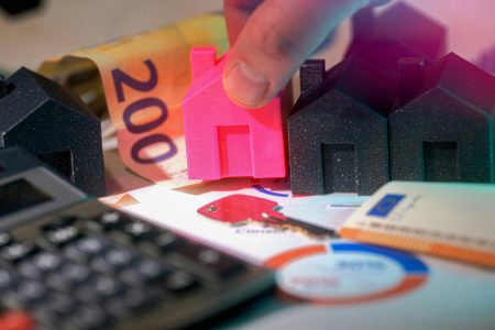 pink and black miniature houses, calculator, graphs, and banknotes